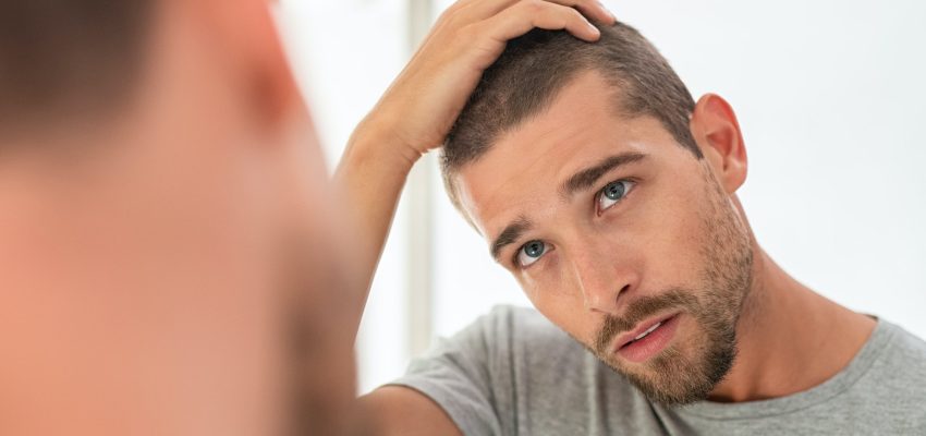 Young man checking hair in mirror